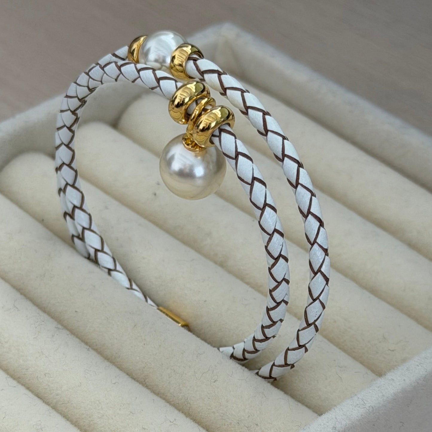 Bracelet with pearl and gold charm on a beige jewelry display