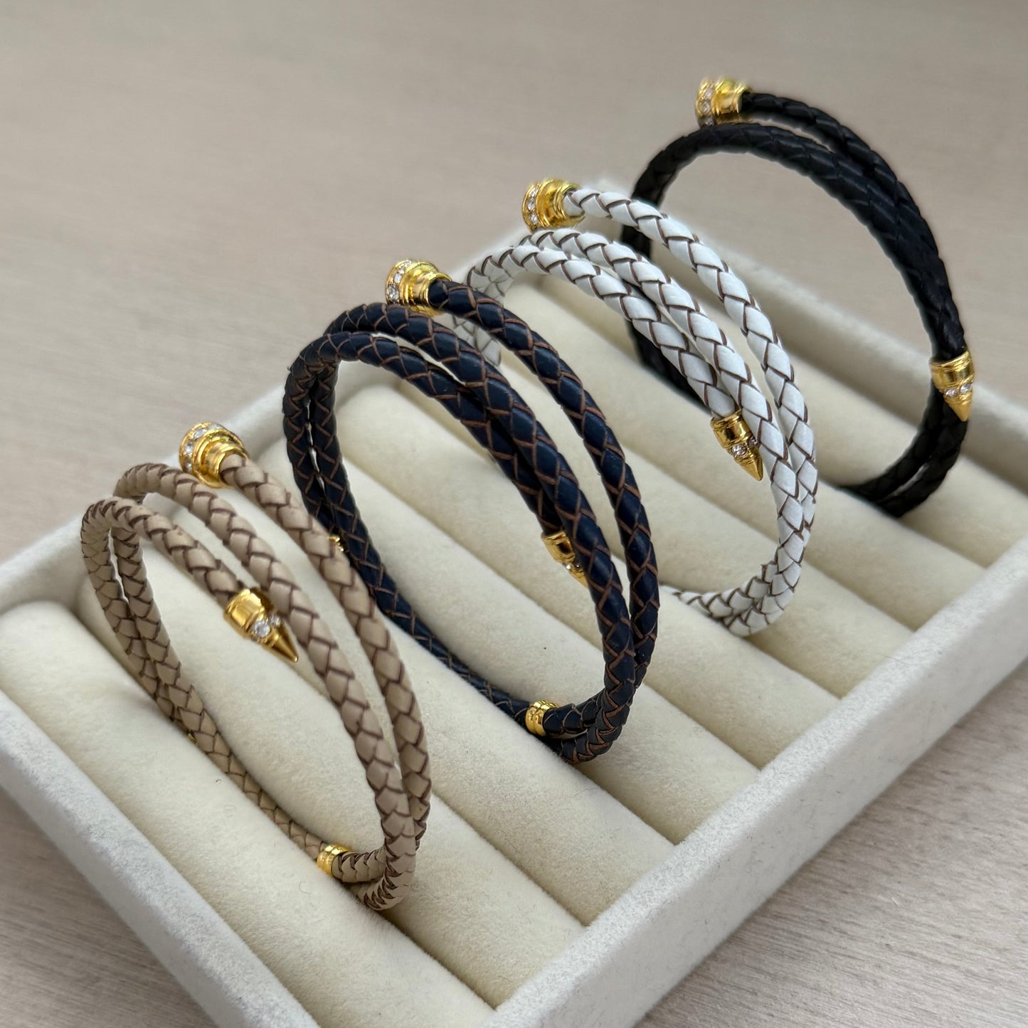 Set of braided bracelets on a white display stand with a neutral background