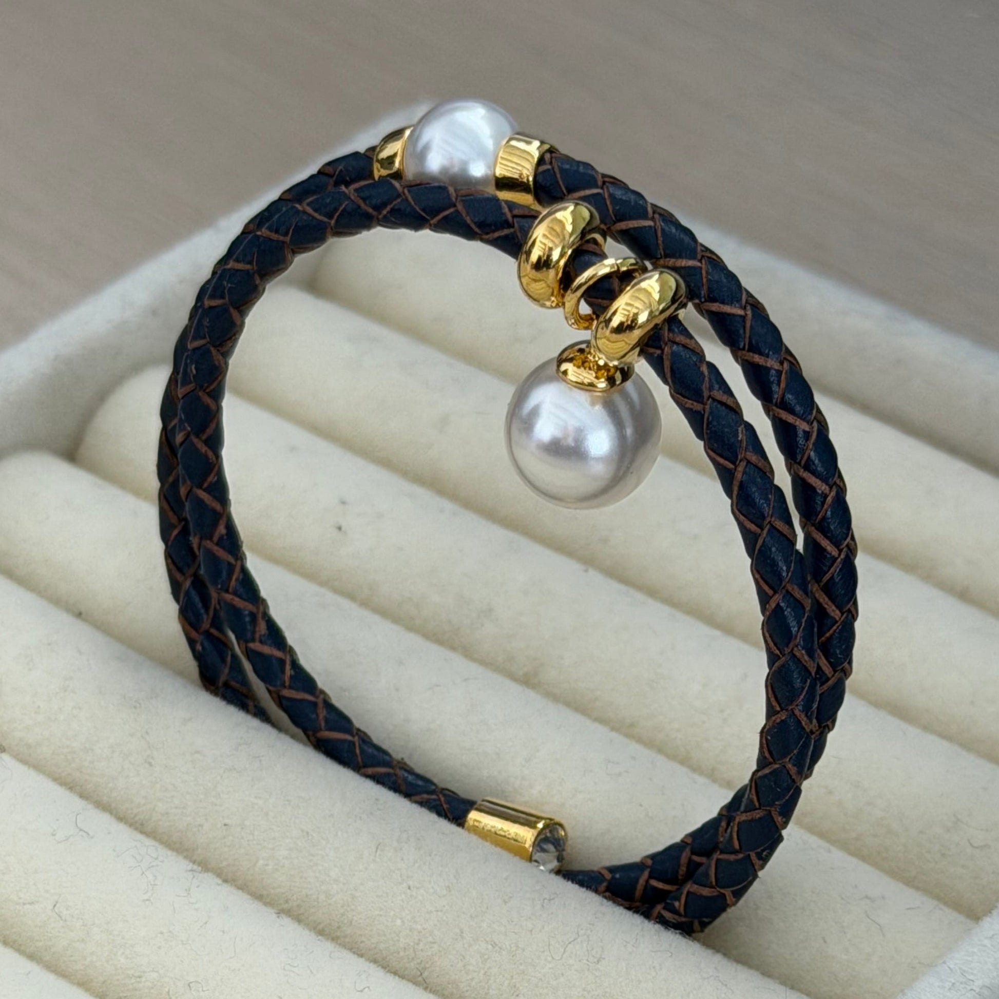 Bracelet with pearls and gold accents on a beige cushioned surface