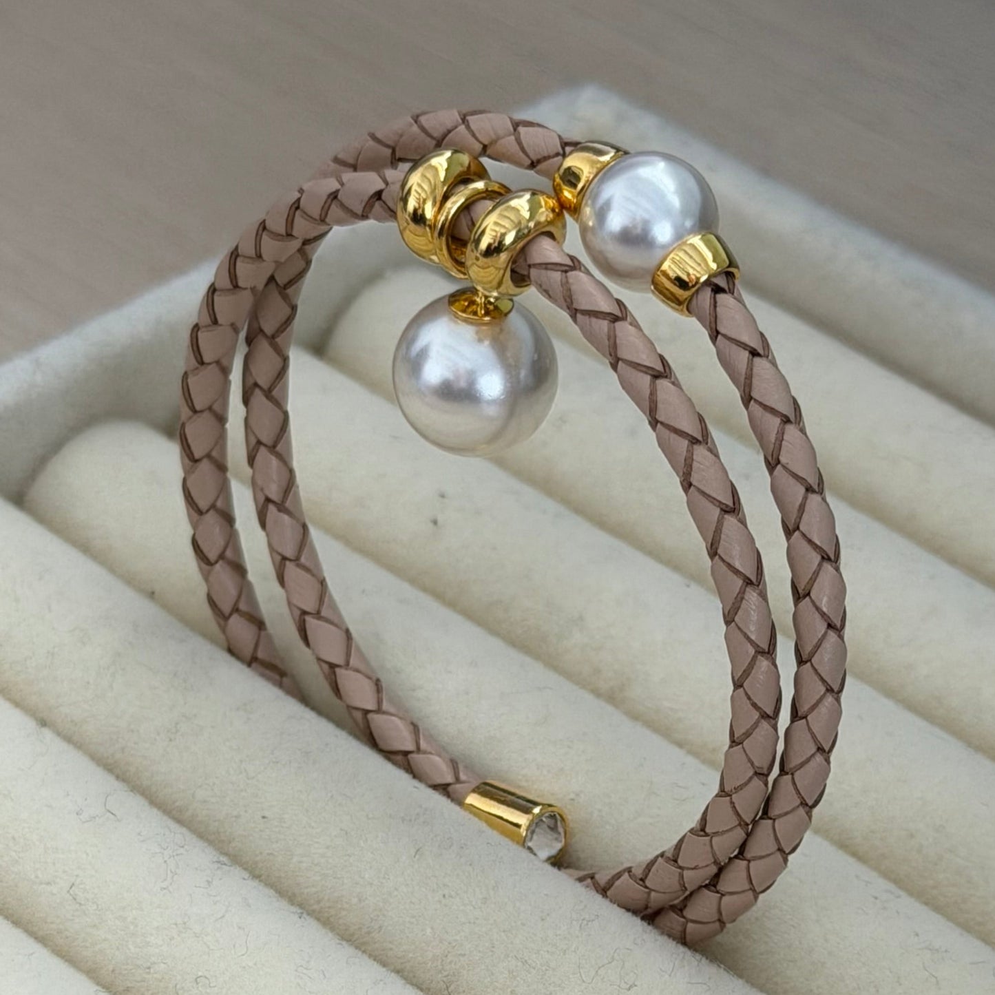 Bracelet with pearls and gold clasps on a beige ring holder
