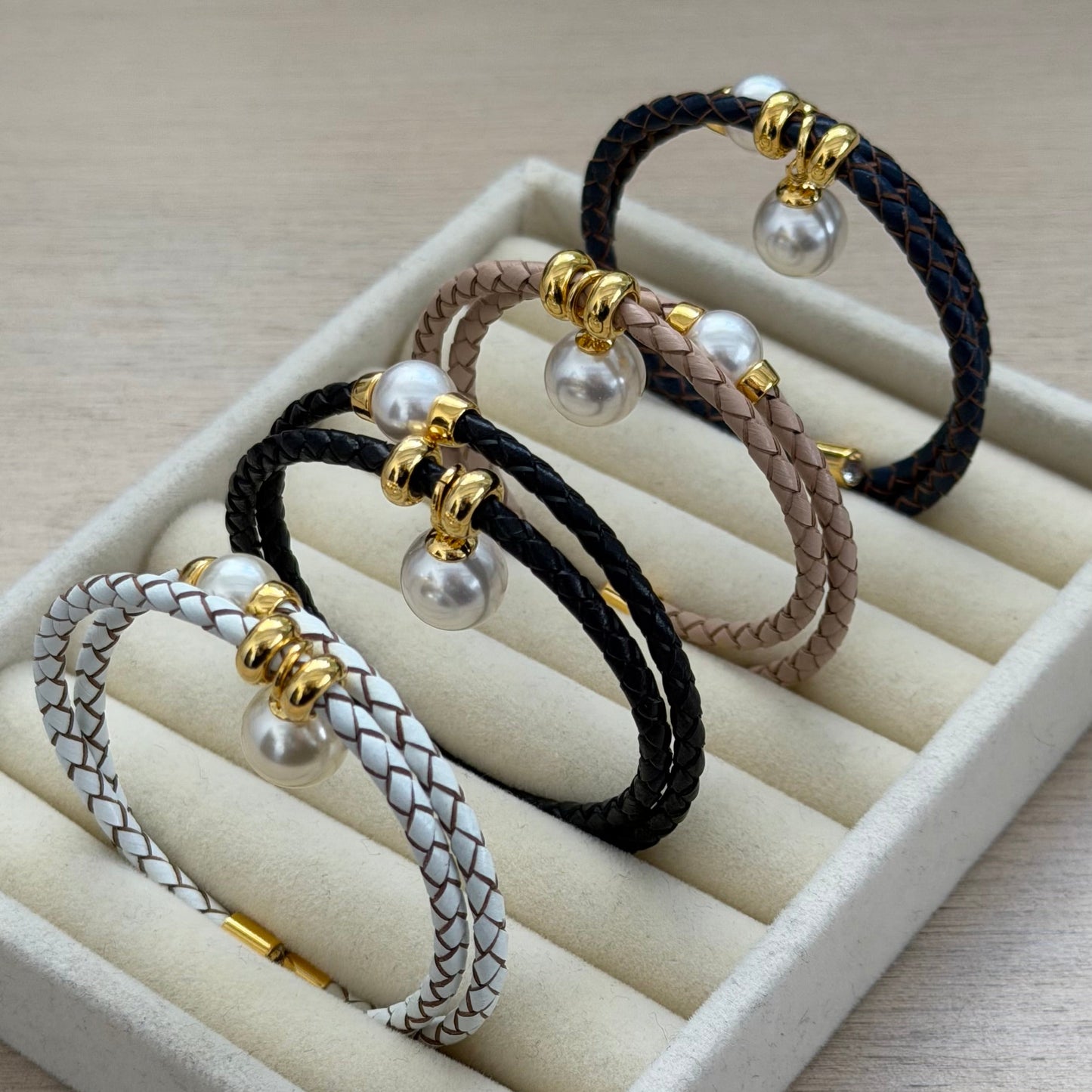 Set of braided hair ties with pearls on a white display stand.