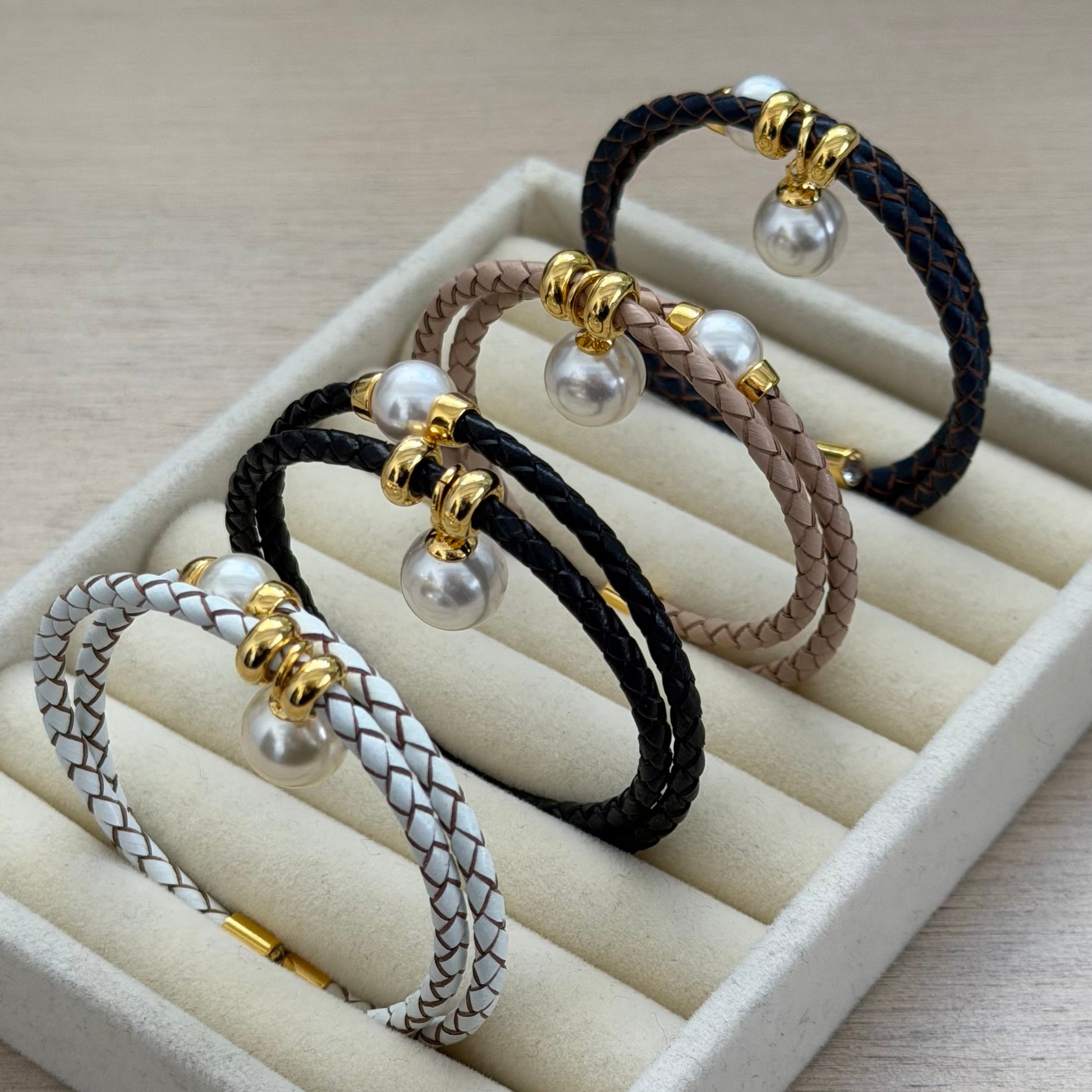Set of braided hair ties with pearls on a white display stand.